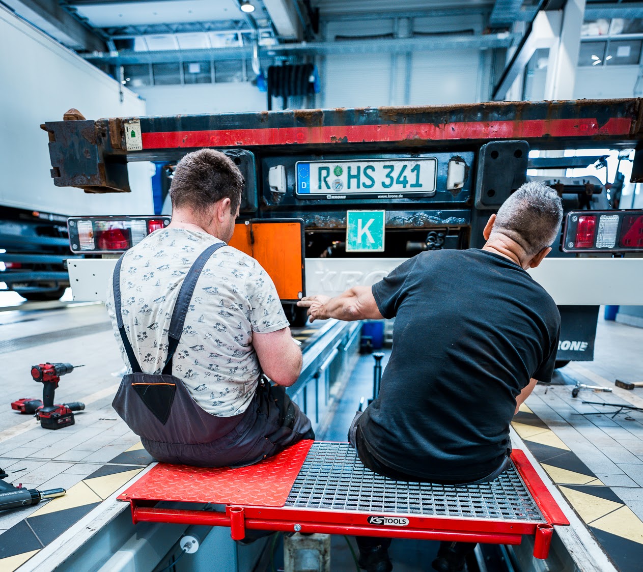 Zwei Werkstattmitarbeiter sitzen an der Werkstattgrube.